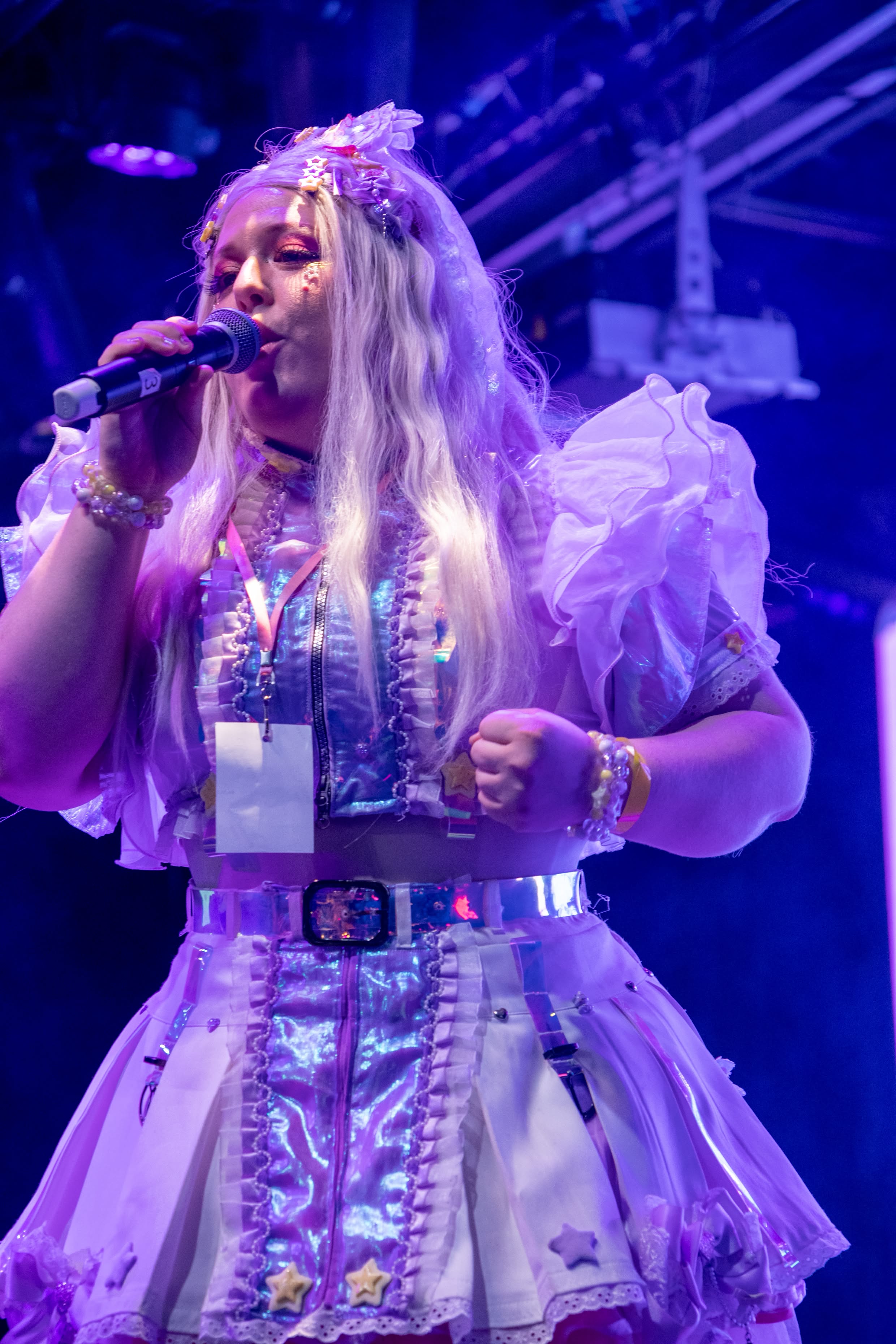 Performer seated on the stage edge, mid-vocal